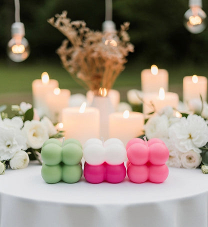 Colorful bubble candles on a table with flowers and hanging lights in the background
